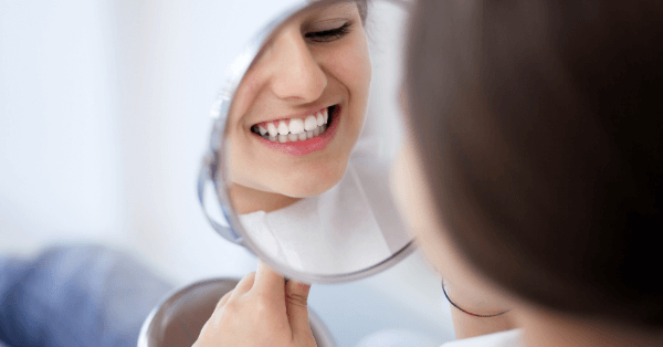 Female looking in the mirror smiling after having dental implants