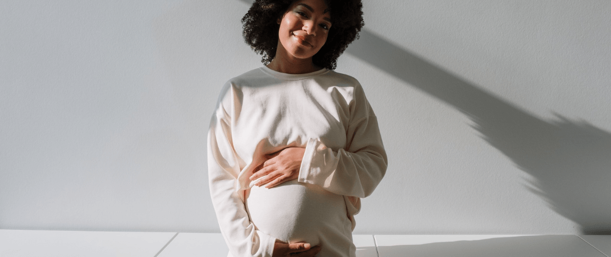 pregnant lady holding her bump smiling at the camera